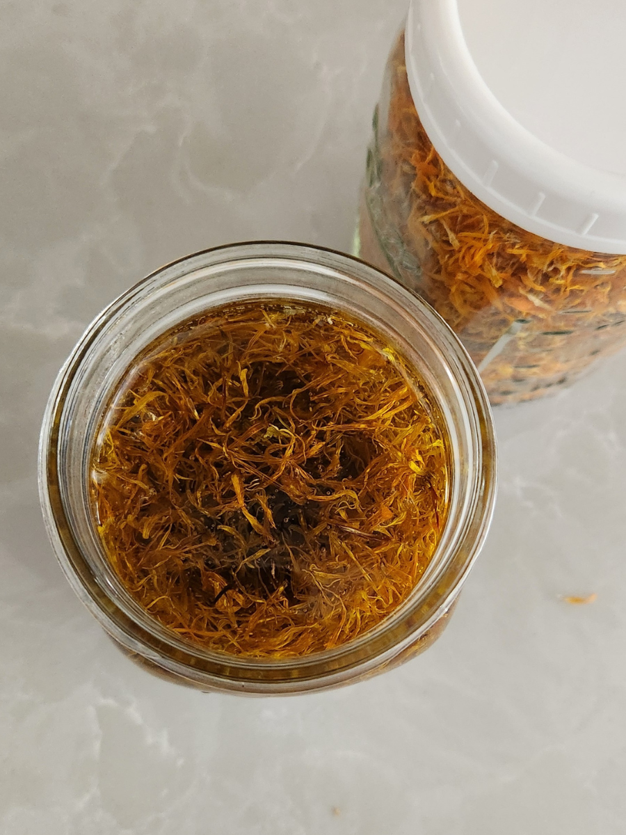 a jar of dried calendula with oil in it 