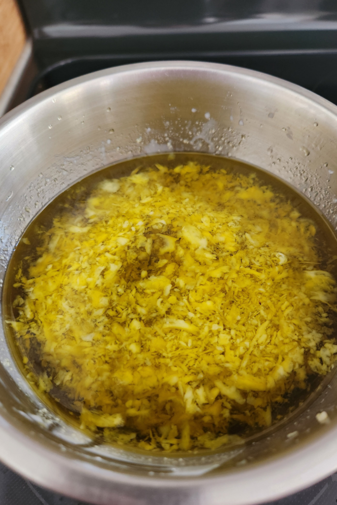 Calendula infused oil, shea butter, and beeswax melting in a double boiler — the first step in making homemade calendula salve