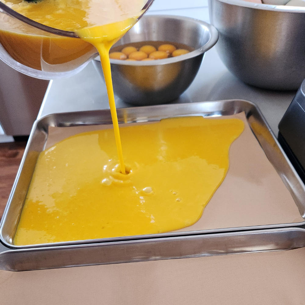 pouring raw eggs in tray to freeze dry