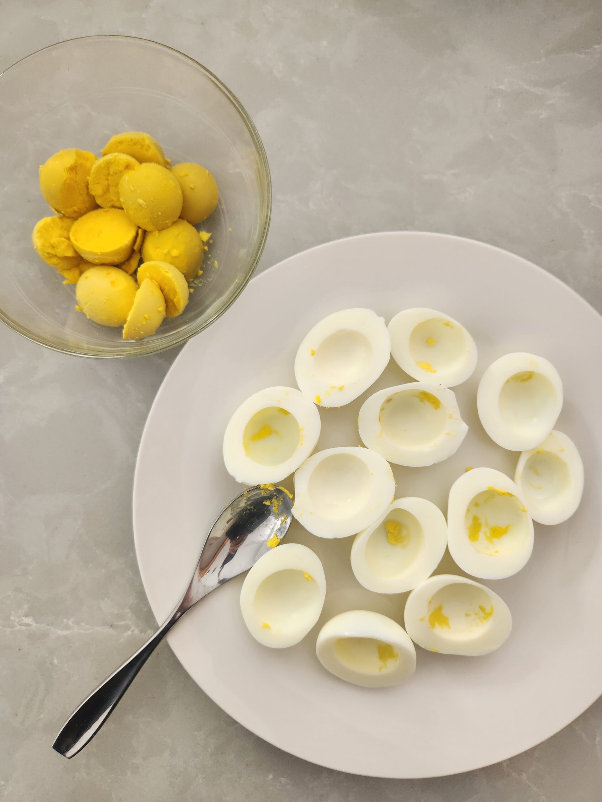 sliced hard-boiled eggs on a plate and egg yolks in a bowl