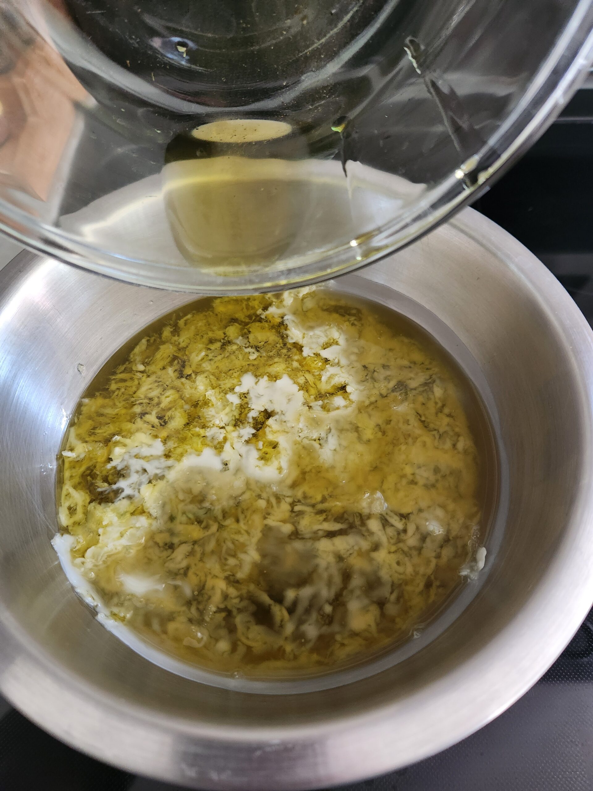 melting yarrow and calendula infused oils with beeswax and shea butter in double boiler