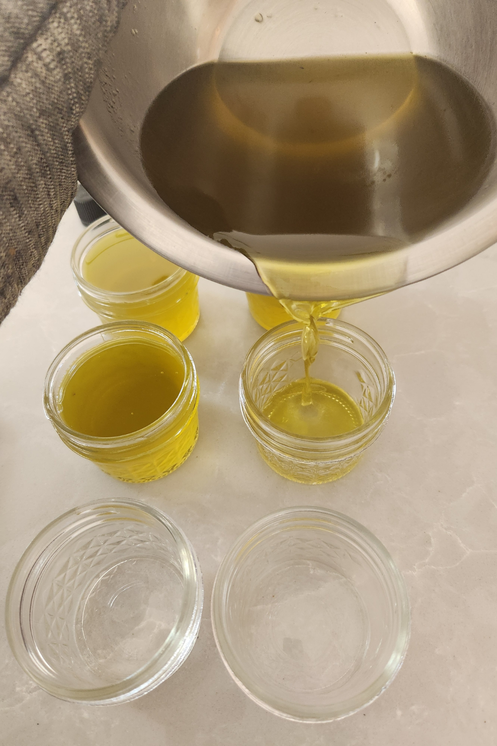 pouring homemade salve into 4 oz glass mason jars