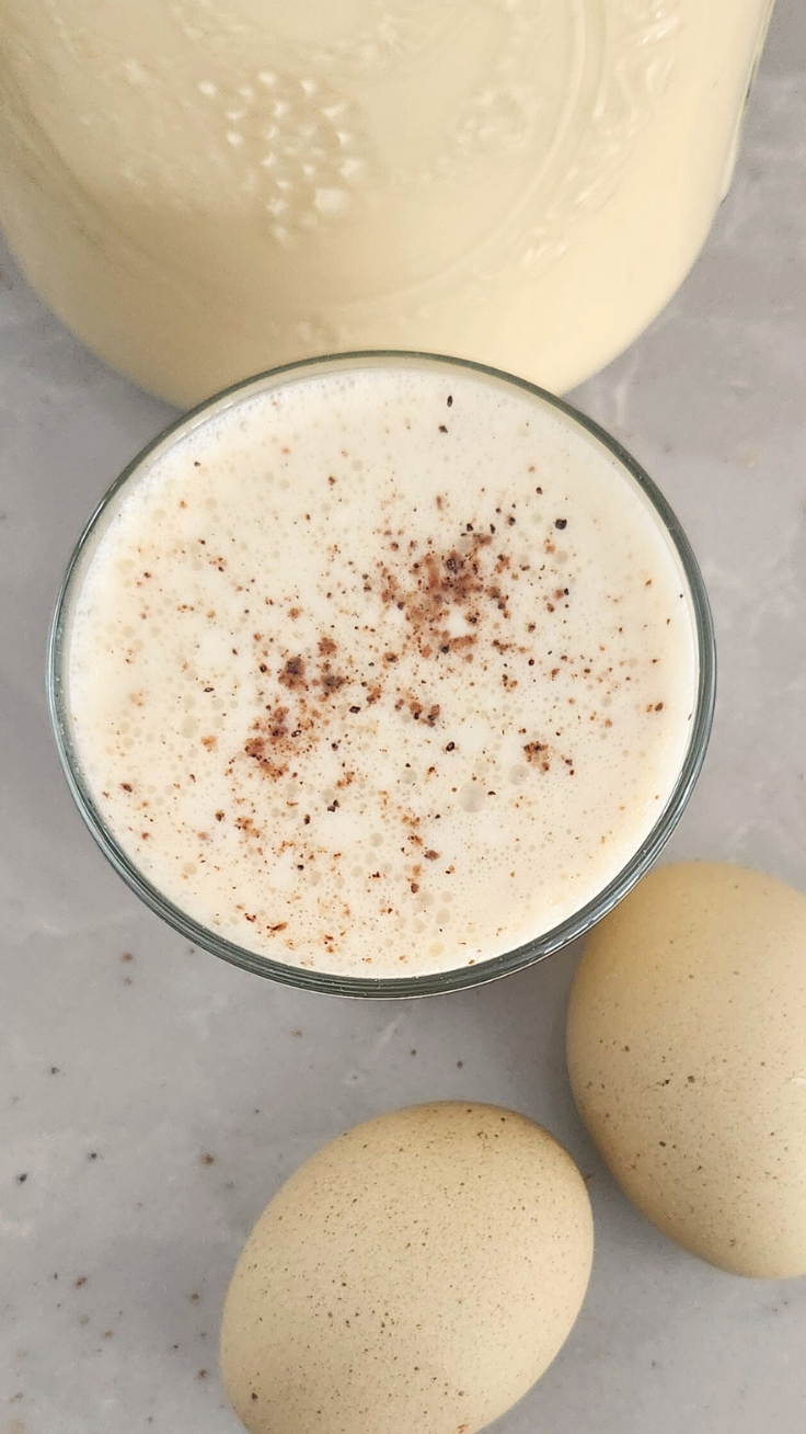 close up of a glass of raw milk eggnog