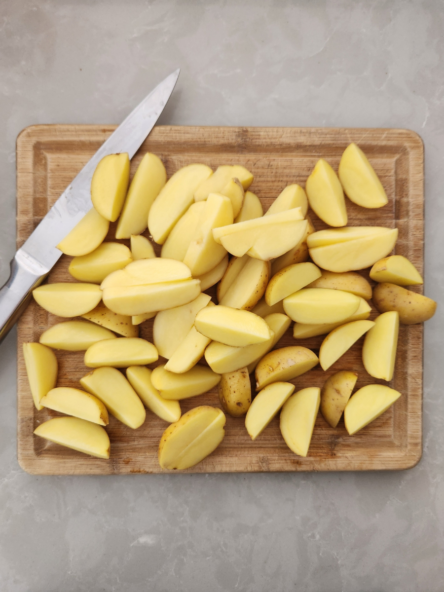 potatoes cut into wedges on a cutting board 