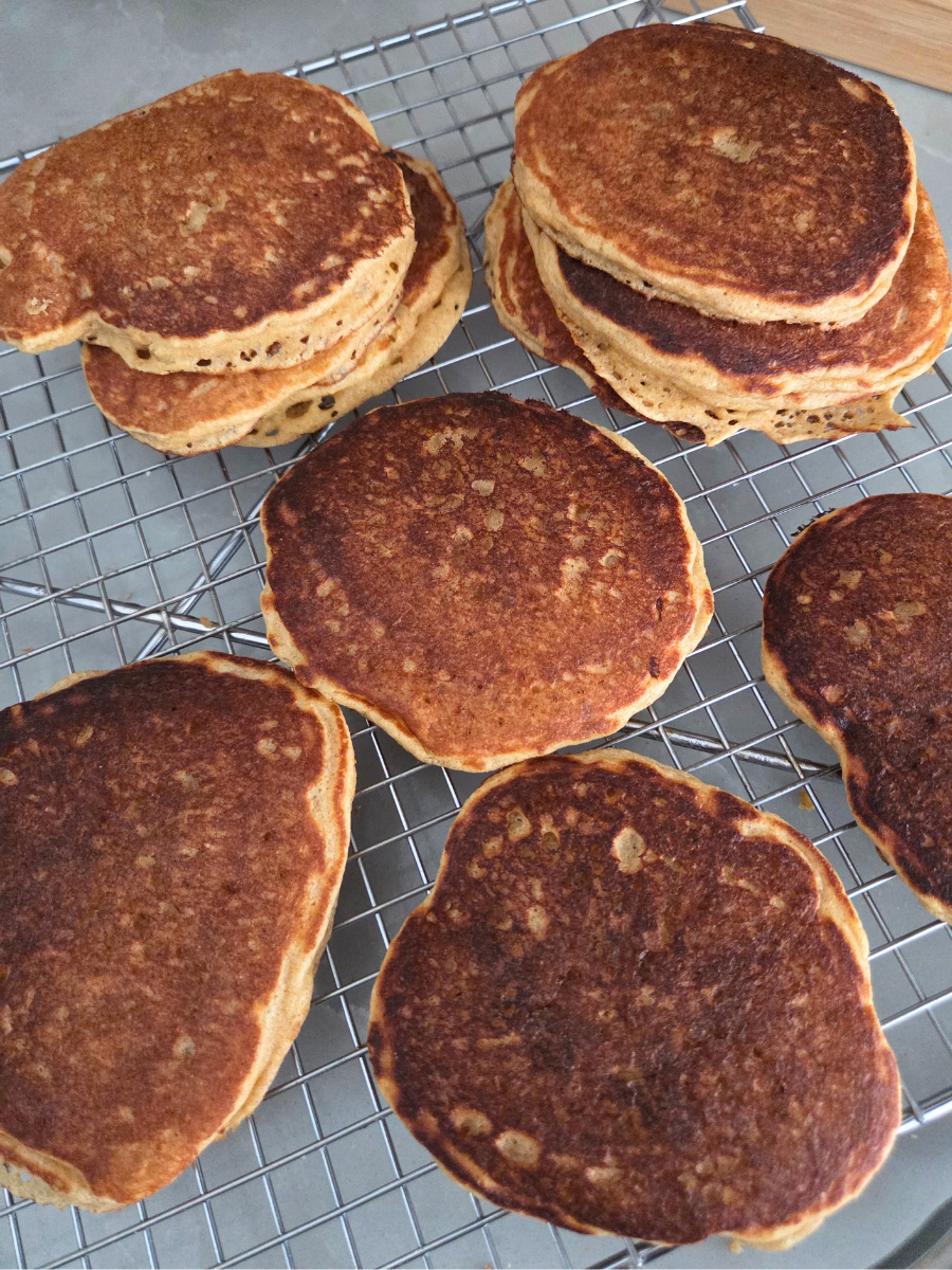 Fresh milled flour pancakes cooling on a wire rack after cooking.
