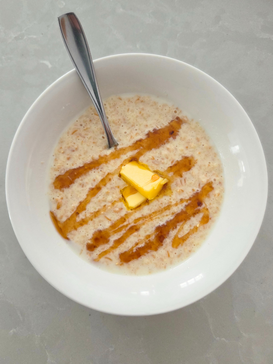 Bowl of warm einkorn cream of wheat topped with butter and maple syrup drizzle.