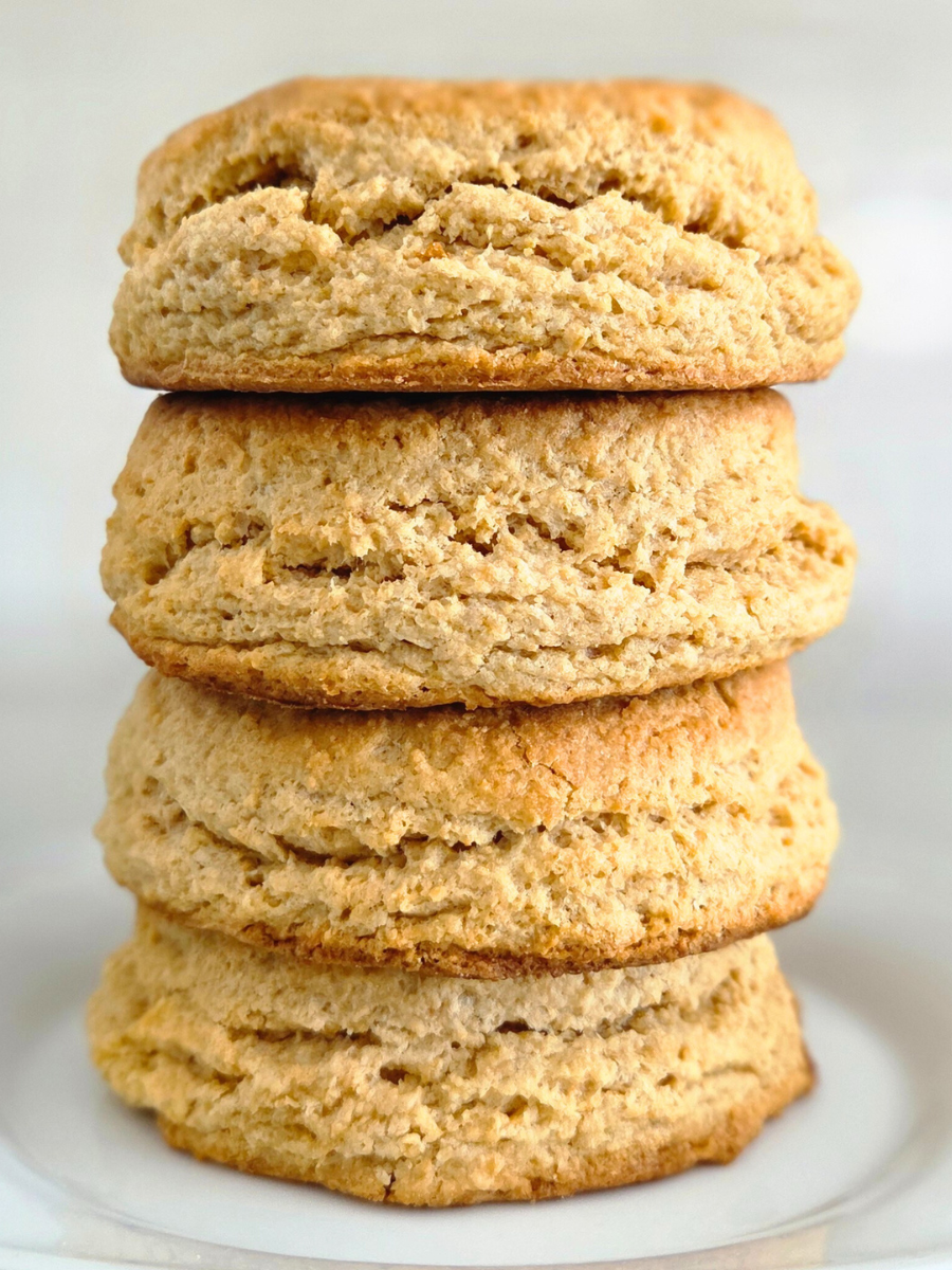 Fluffy and flaky fresh milled flour biscuits stacked on a white plate, showing tall rise and soft layers