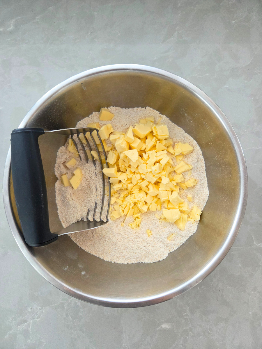 Cold butter being cut into fresh milled flour using a pastry cutter