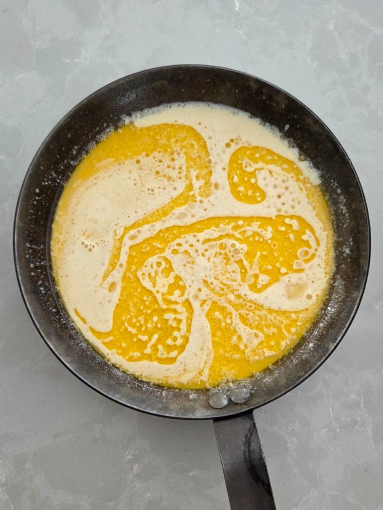 Dutch baby pancake batter poured into a hot buttered cast iron skillet