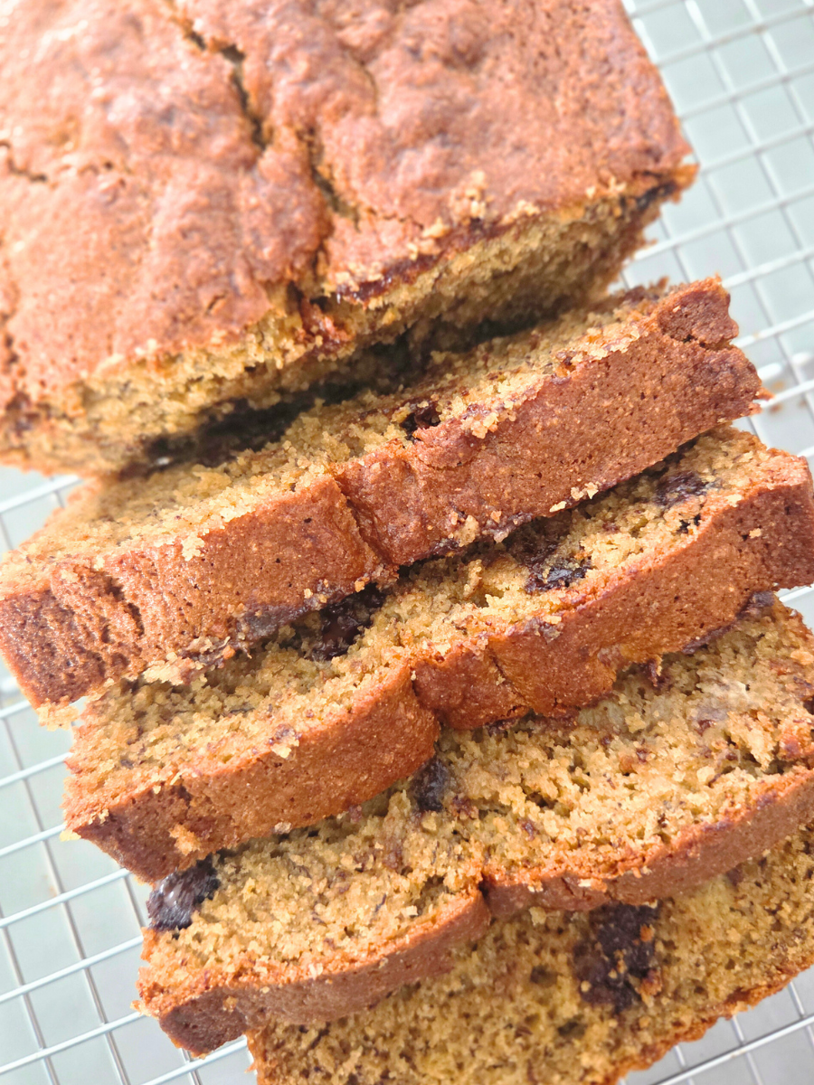 Slices of fresh milled flour banana bread with chocolate chips on a cooling rack.