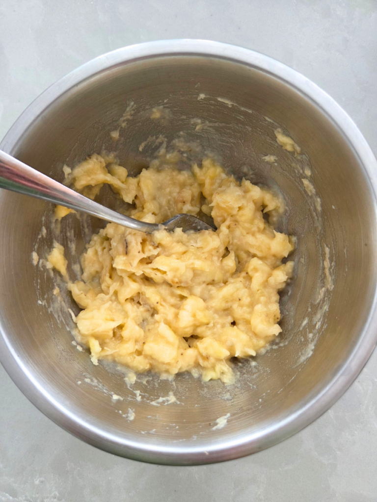 Mashed overripe bananas in a bowl for fresh milled banana bread.