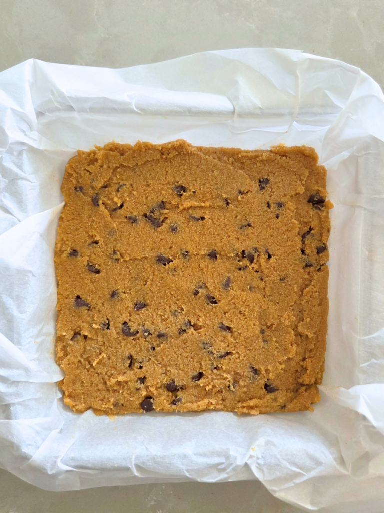 Banana blondie batter made with fresh milled flour pressed into a parchment-lined pan
