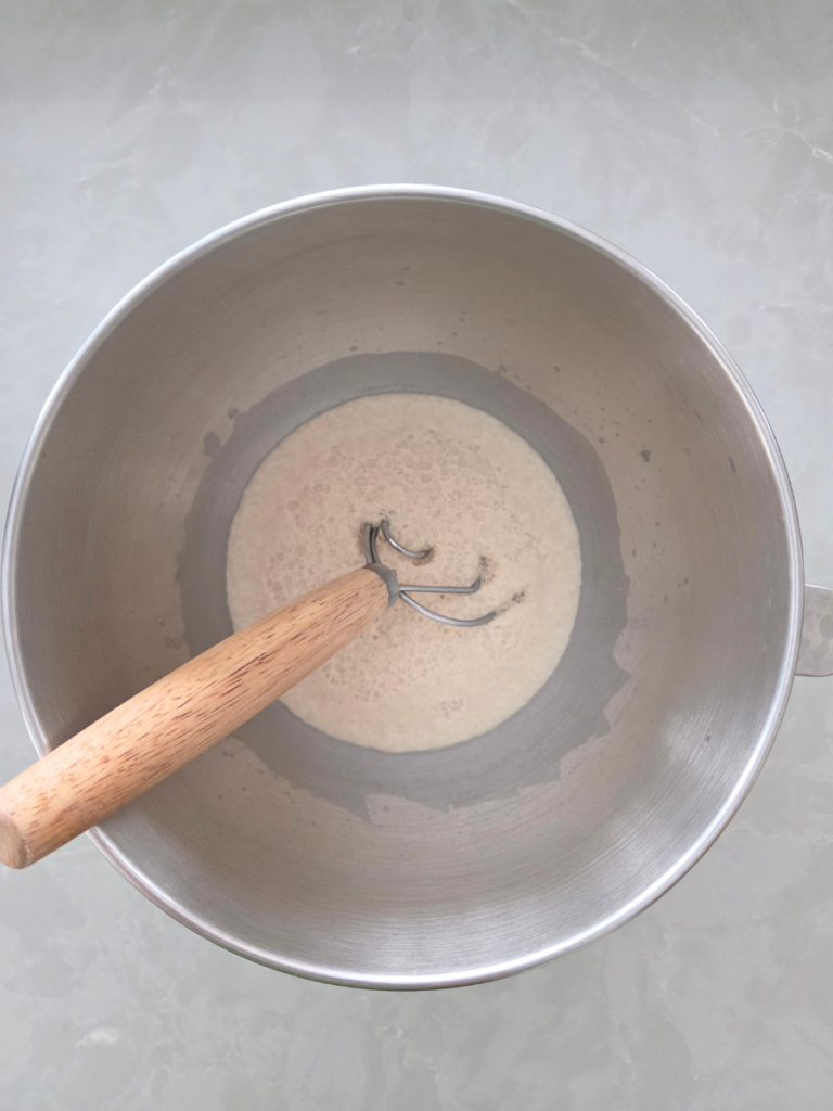 Yeast mixture with warm water and sugar in a stand mixer bowl before adding flour.