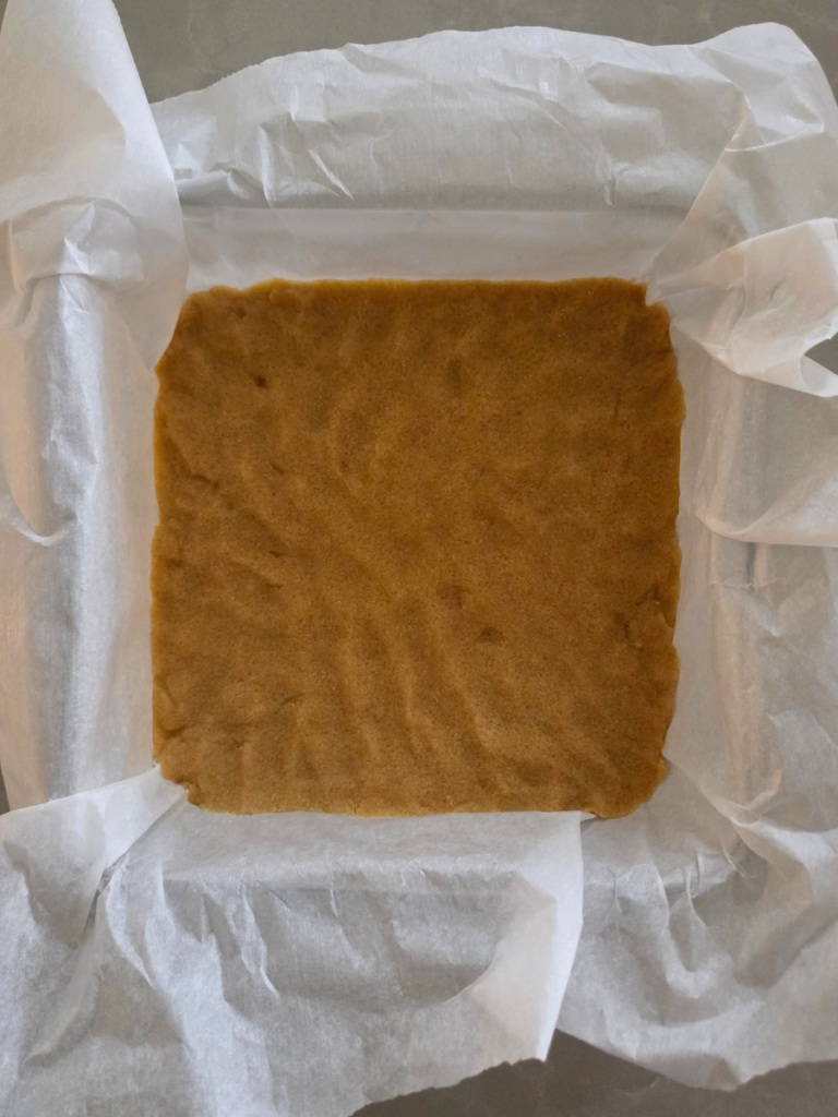 Shortbread dough pressed into parchment-lined pan
