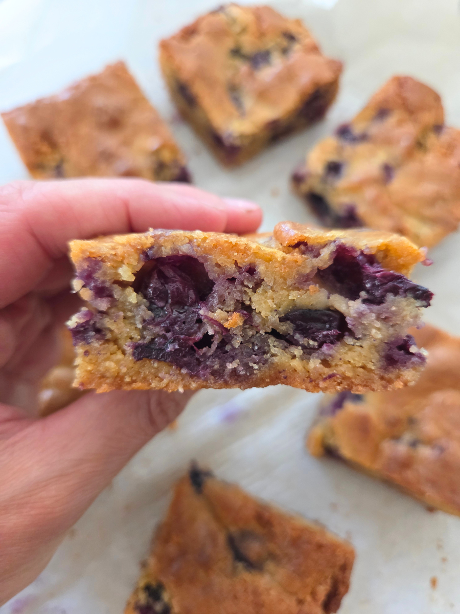 Fresh milled flour blueberry blondie cut open to show the soft, buttery center packed with baked blueberries.