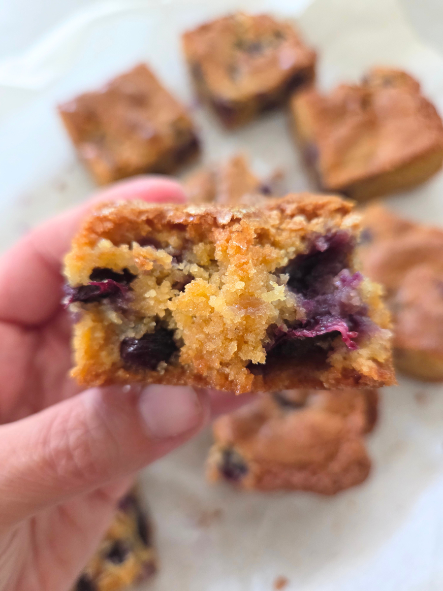 Close-up of a soft, chewy freshly milled blueberry blondie showing a moist center with juicy baked blueberries.