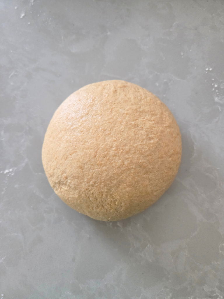Smooth dough ball after kneading and resting on the countertop.