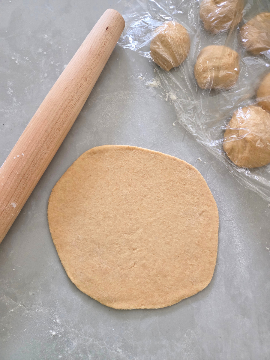 Rolled dough round ready to cook in a hot skillet, with remaining dough covered to prevent drying out.