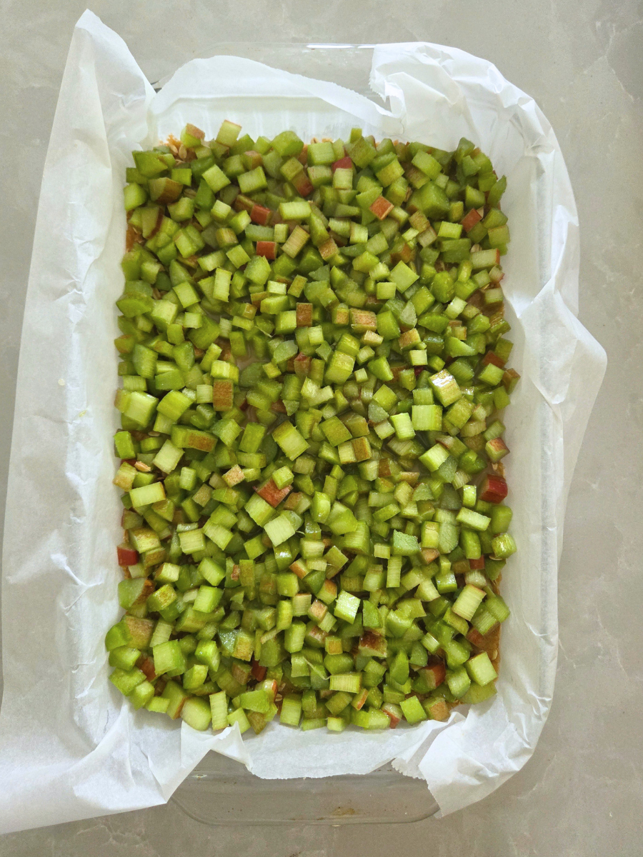 Fresh chopped rhubarb evenly spread over the pressed crust in a parchment-lined baking pan.
