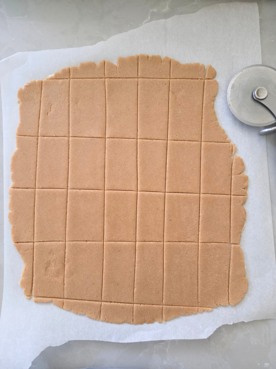 Rolled graham cracker dough cut into even rectangles with a pizza cutter