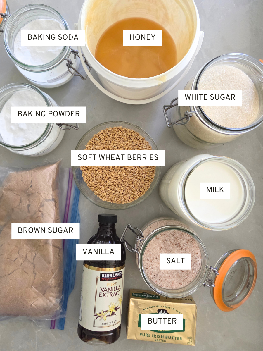 Ingredients for fresh milled flour graham crackers including soft wheat berries, butter, honey, sugar, milk, vanilla, salt, baking soda, and baking powder.