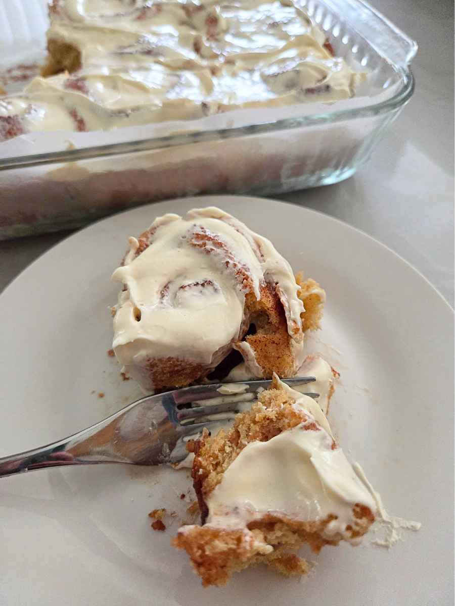 Fresh milled flour cinnamon roll with cream cheese frosting showing the soft interior on a plate.