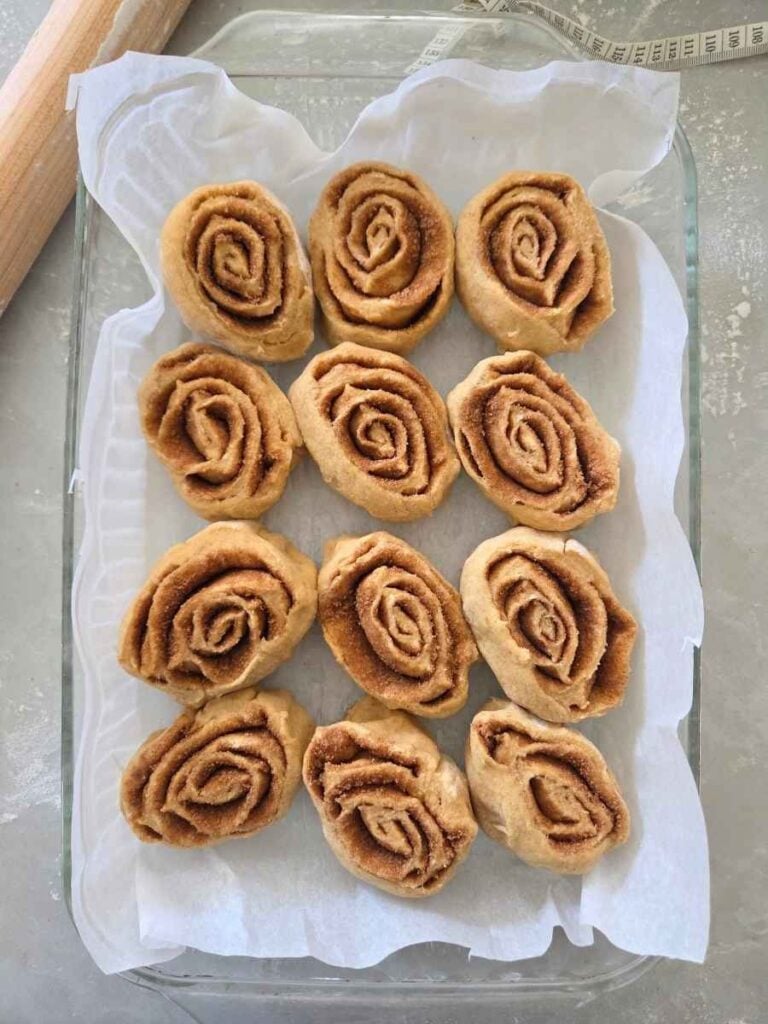 Shaped cinnamon rolls before the second rise in a baking dish.