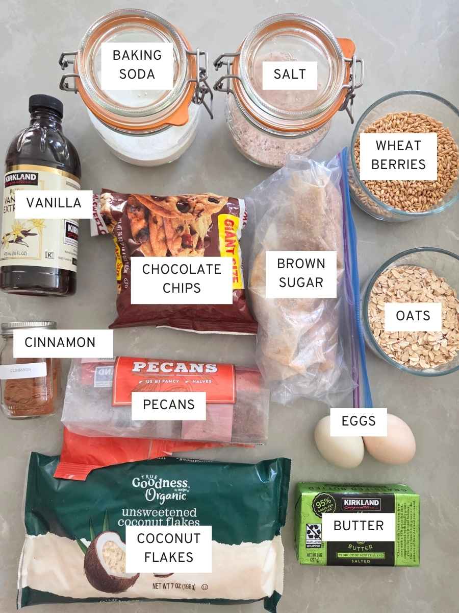 Ingredients for fresh milled flour cowboy cookies including wheat berries, oats, chocolate chips, coconut, pecans, and brown sugar