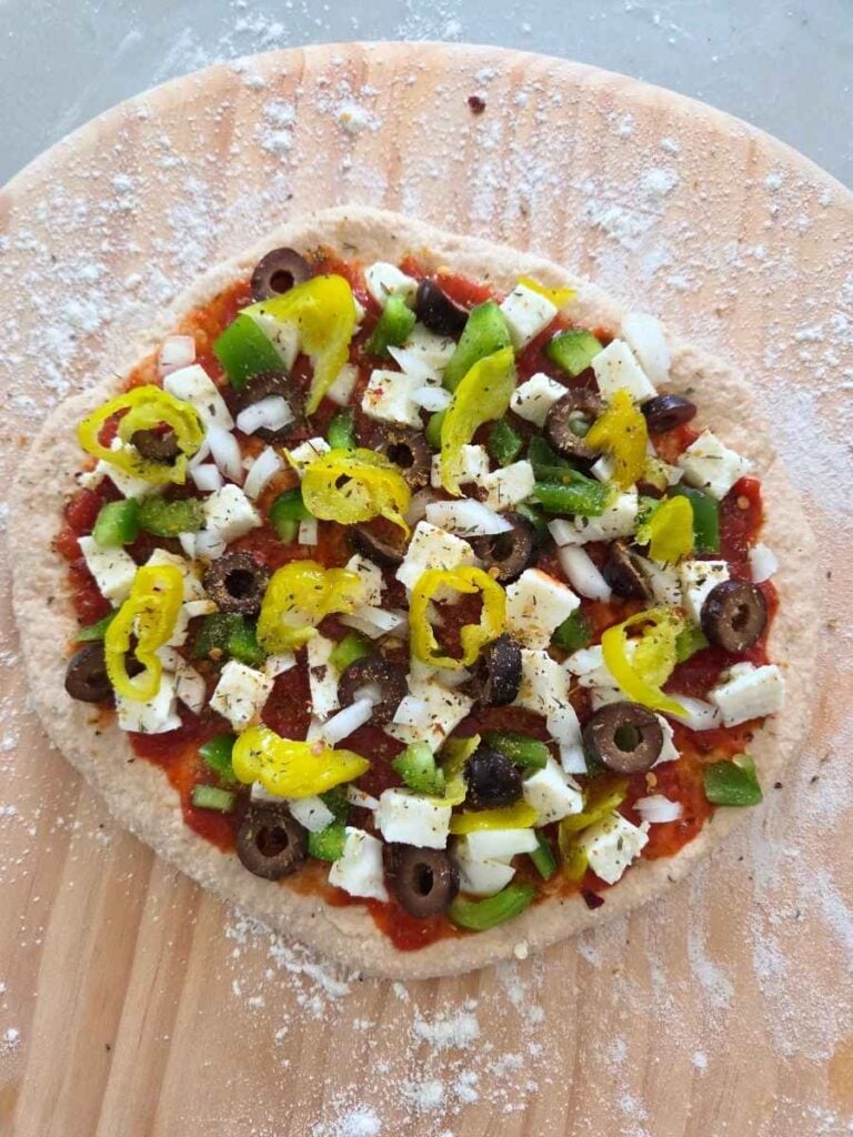 Fresh milled flour pizza dough topped with mozzarella, olives, peppers, onions, and banana peppers