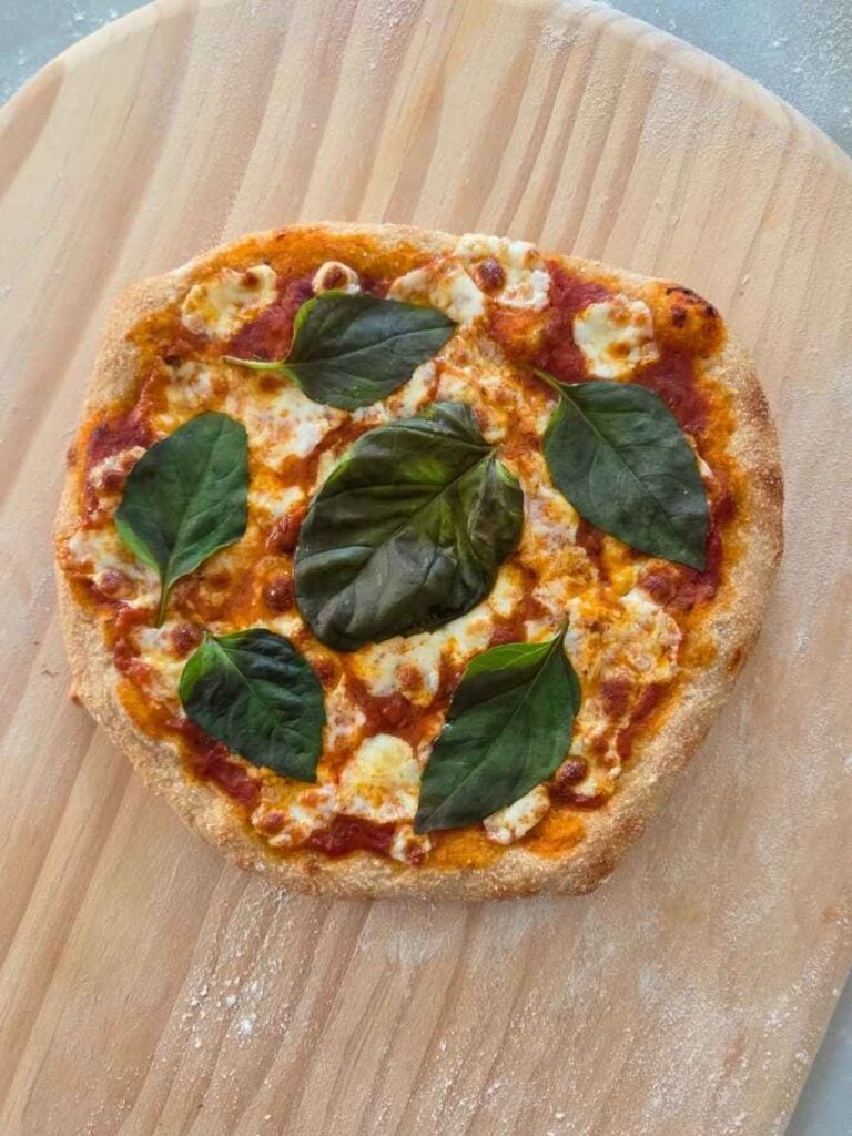 Homemade fresh milled flour pizza topped with melted mozzarella and fresh basil
