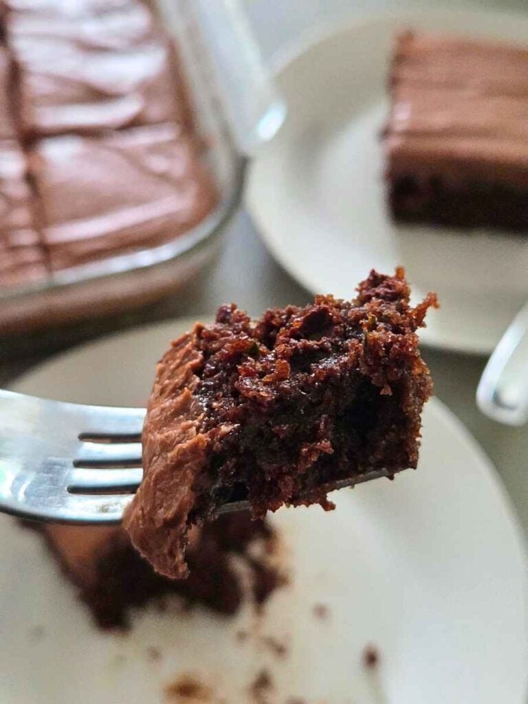 Close-up of a bite of fresh milled flour chocolate zucchini cake on a fork, showing its rich, moist chocolate crumb.