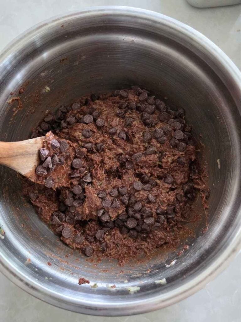 Semi-sweet chocolate chips being mixed into the chocolate zucchini cake batter.