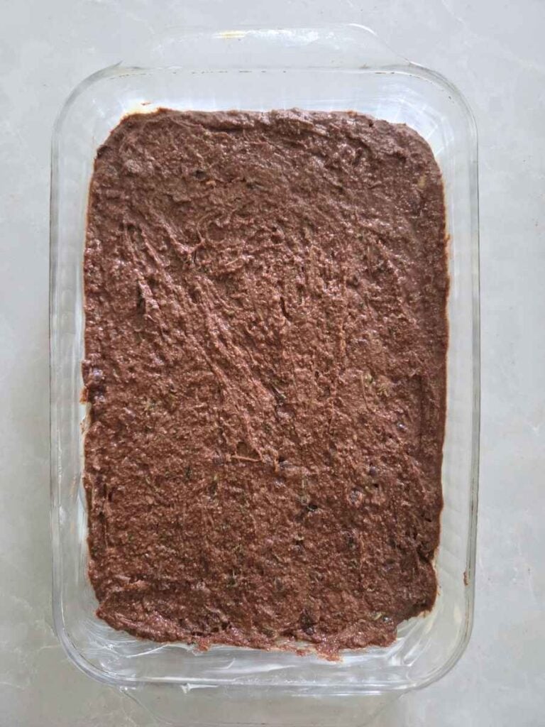 Chocolate zucchini cake batter spread evenly in a 9x13-inch baking dish.