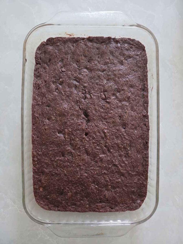 Baked chocolate zucchini cake cooling in a glass baking dish.