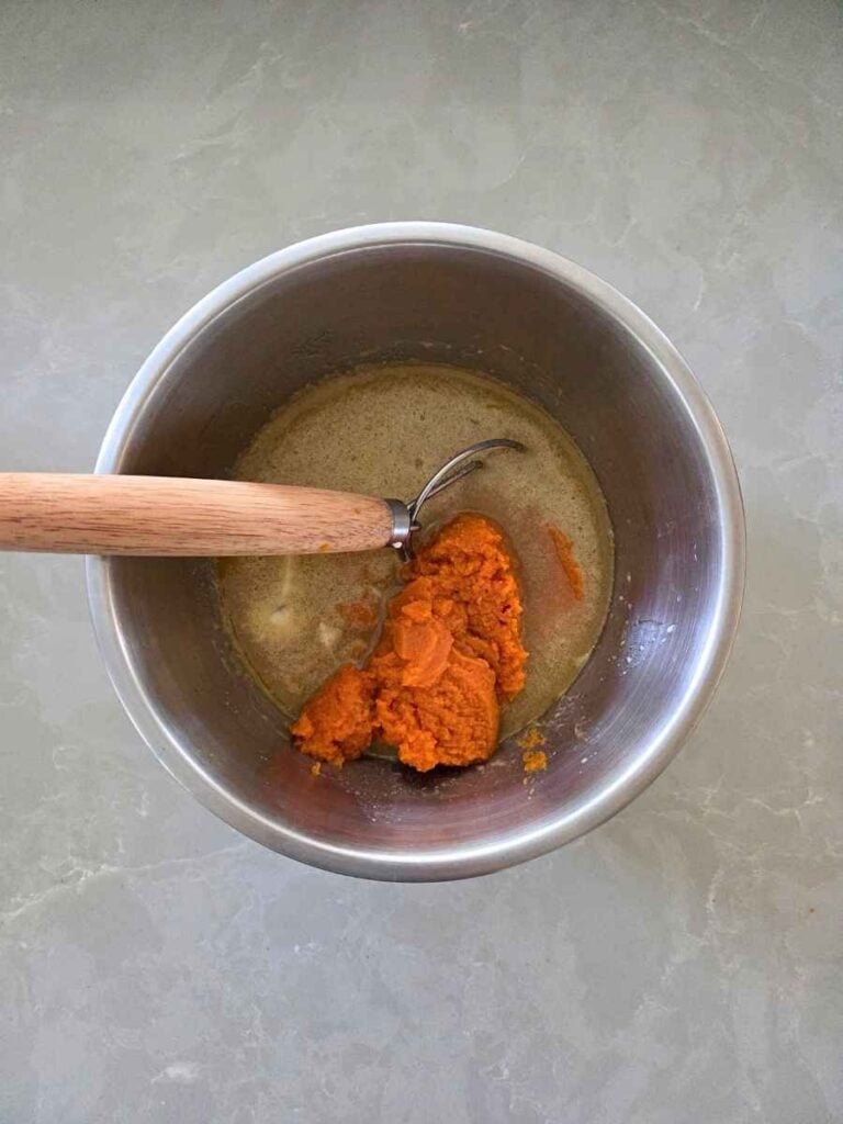 Pumpkin puree added to the wet ingredients in a mixing bowl.