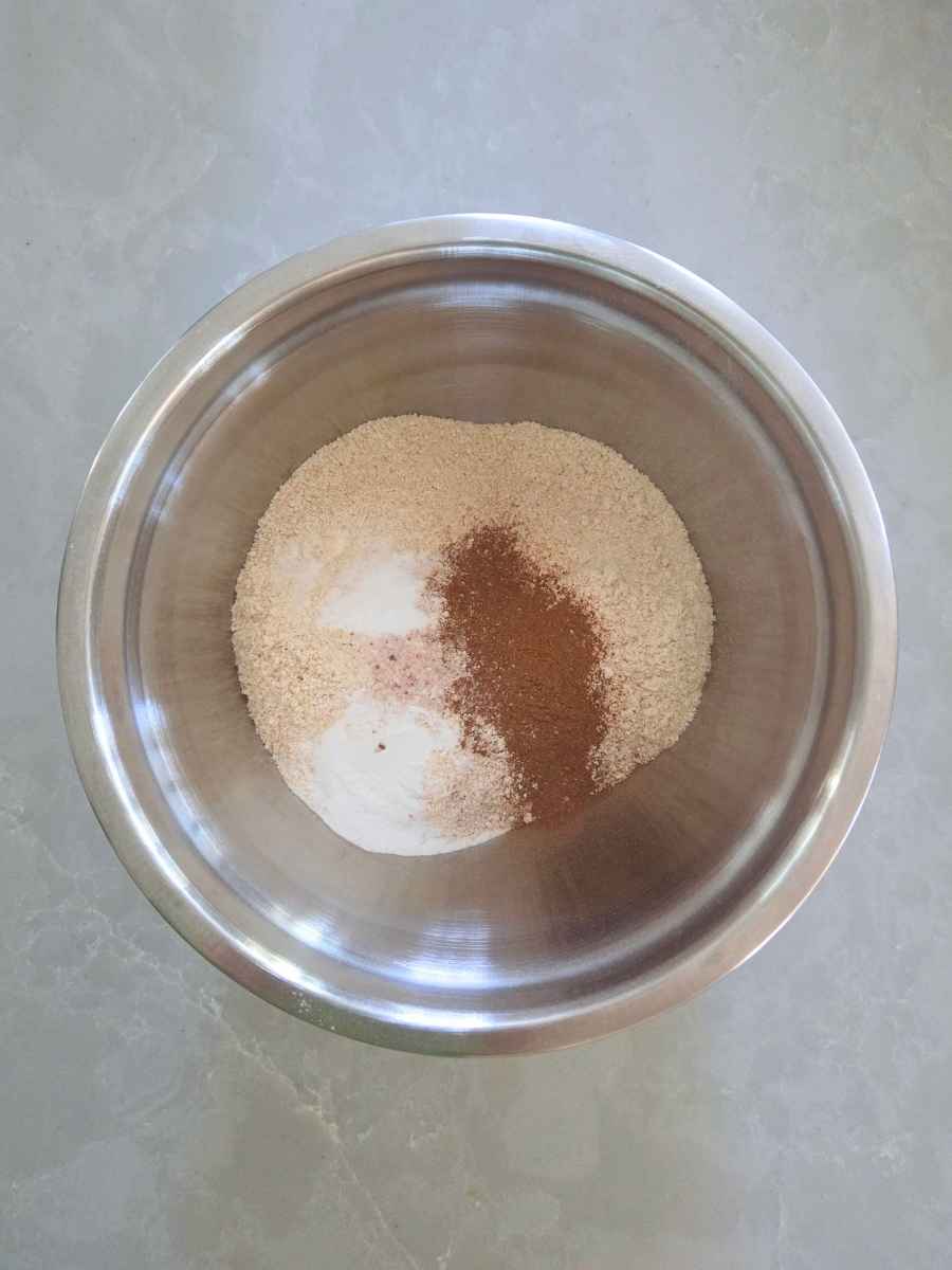 Freshly milled wheat flour, pumpkin pie spice, baking powder, baking soda, and salt in a mixing bowl