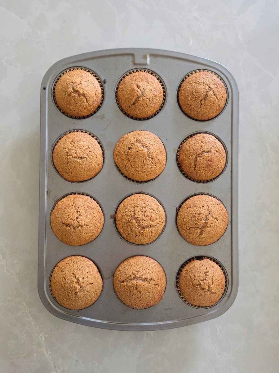 Freshly baked muffins with golden brown domed tops in the muffin pan