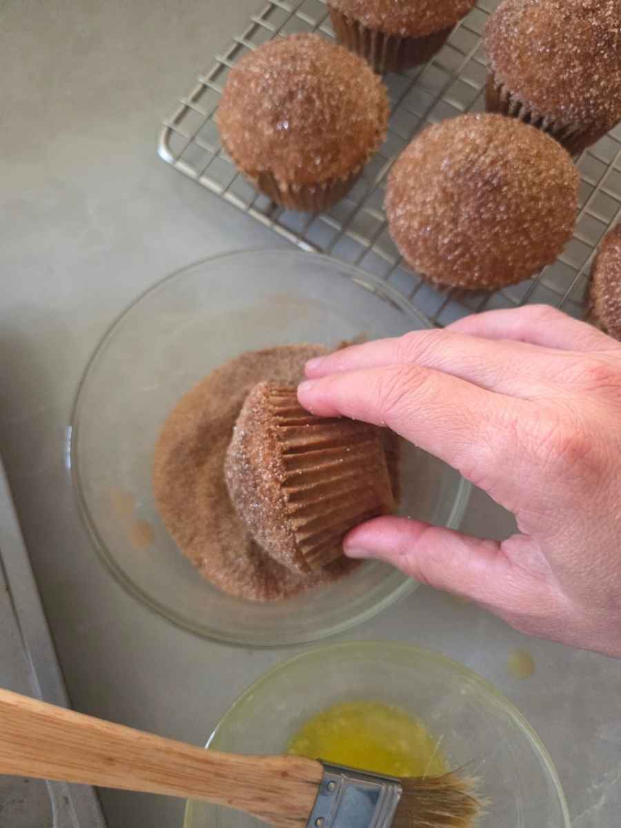 Warm muffin dipped in cinnamon sugar with melted butter and pastry brush nearby
