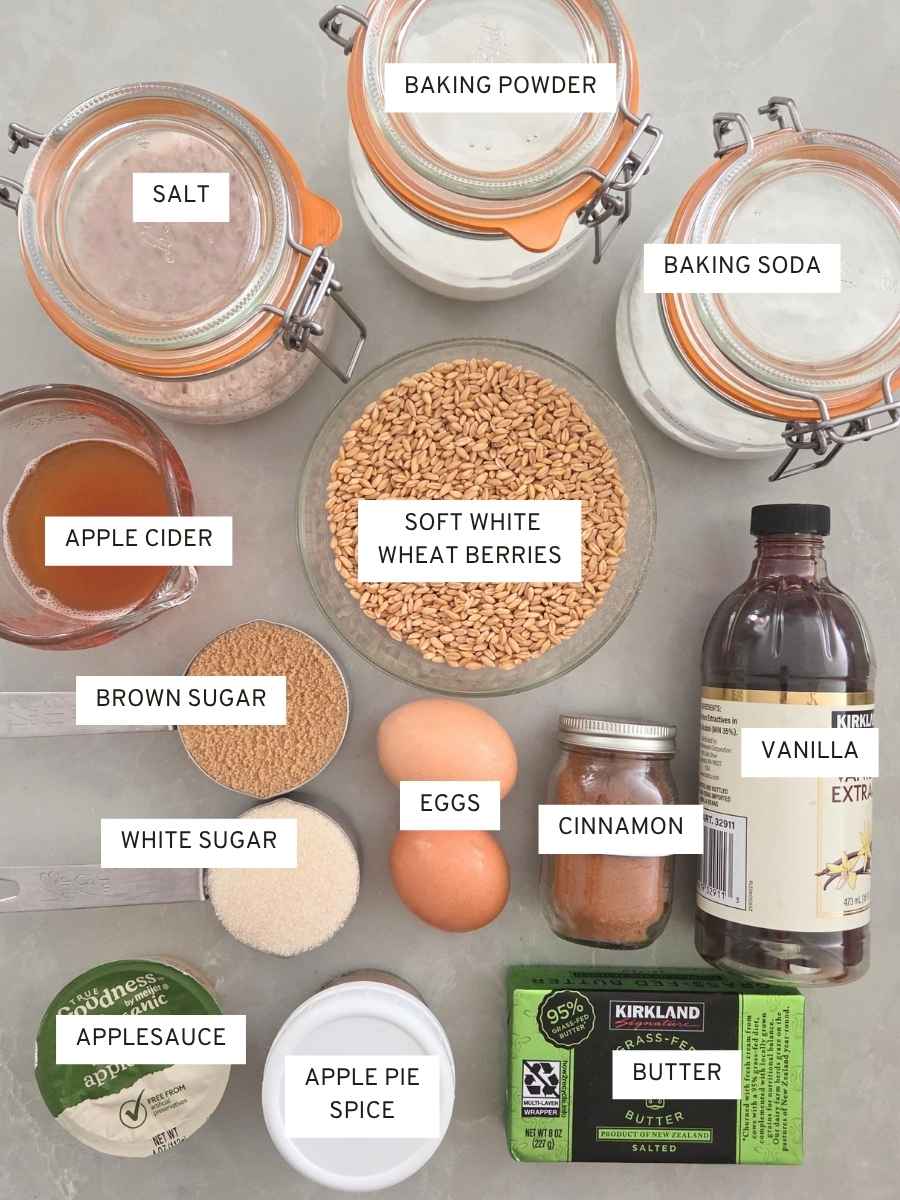 Ingredients for fresh milled flour apple cider donut muffins including soft white wheat berries, apple cider, applesauce, eggs, butter, and spices