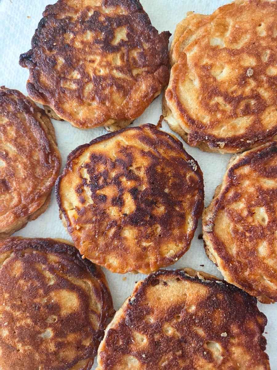 Overhead view of homemade fresh milled flour apple fritter pancakes with golden brown surfaces and rustic, crispy edges.
