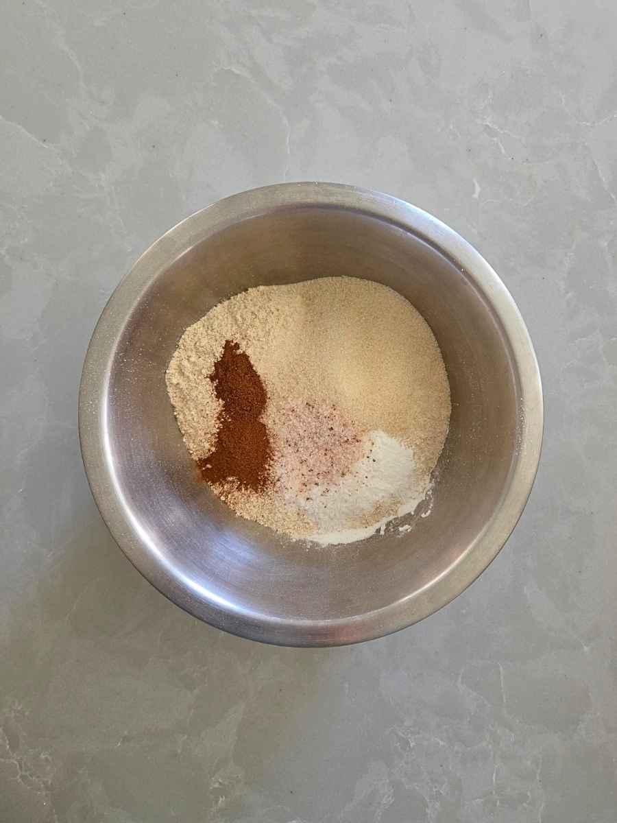 Flour, cinnamon, sugar, baking powder, and salt in a stainless steel mixing bowl.